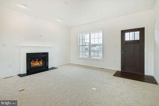 unfurnished living room featuring a fireplace with flush hearth, light carpet, visible vents, and baseboards