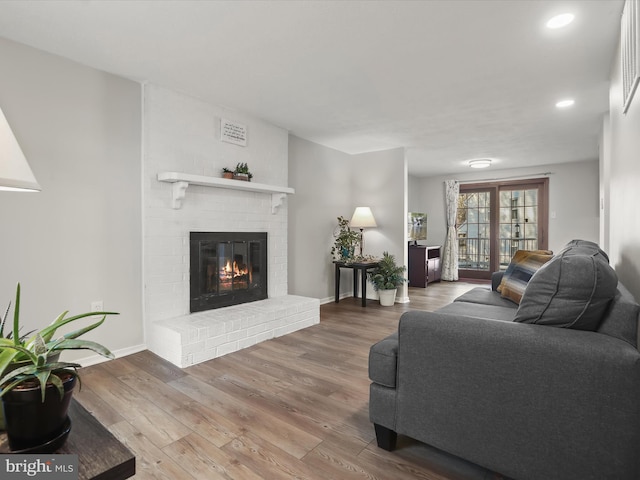 living area with a brick fireplace, baseboards, wood finished floors, and recessed lighting