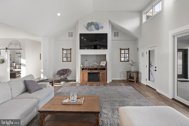 living room featuring high vaulted ceiling, visible vents, and wood finished floors