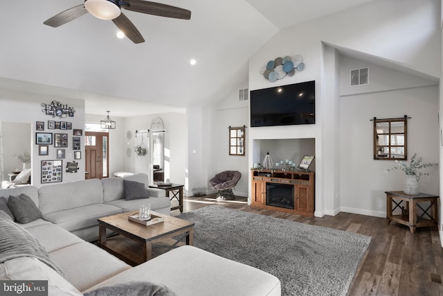 living room with baseboards, visible vents, dark wood-type flooring, a fireplace, and high vaulted ceiling