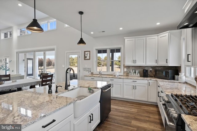 kitchen with dark wood-type flooring, wall chimney range hood, gas range, black microwave, and dishwasher