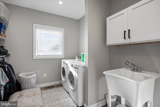 laundry area featuring cabinet space, baseboards, a sink, and independent washer and dryer