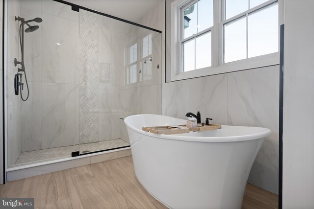 bathroom with a soaking tub, a shower stall, and tile walls