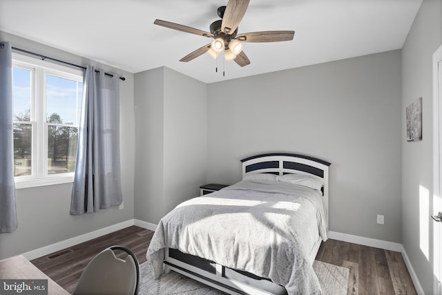 bedroom featuring a ceiling fan, visible vents, baseboards, and wood finished floors