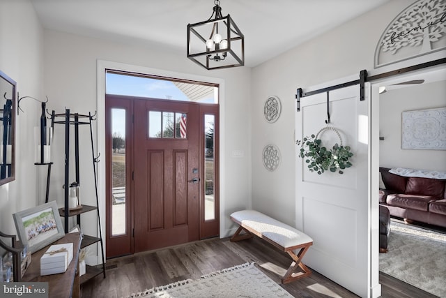 entrance foyer featuring a barn door, an inviting chandelier, and wood finished floors