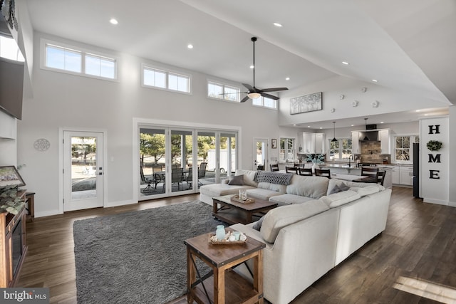 living room with ceiling fan, recessed lighting, dark wood-type flooring, a high ceiling, and baseboards