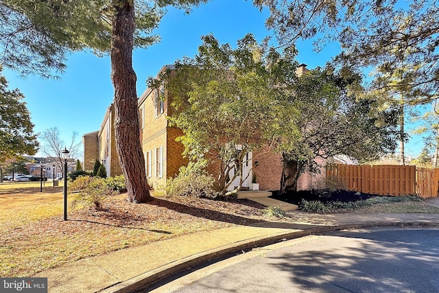 view of home's exterior featuring brick siding and fence