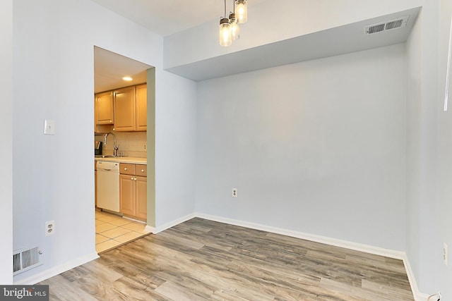 unfurnished dining area featuring visible vents, light wood-style flooring, baseboards, and a sink