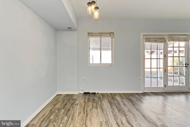 spare room with visible vents, baseboards, and wood finished floors