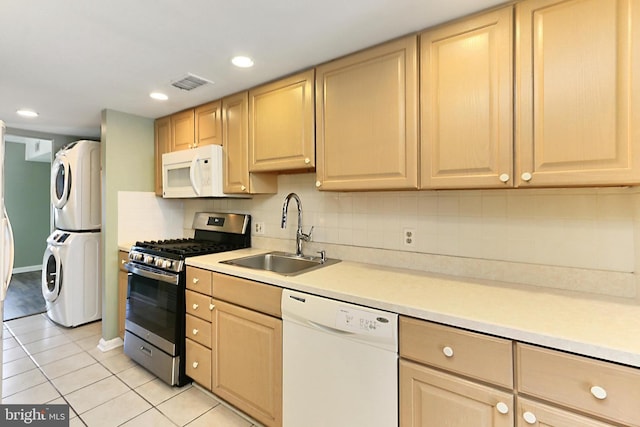 kitchen featuring white appliances, visible vents, light brown cabinetry, a sink, and stacked washer and clothes dryer