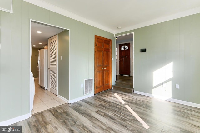 spare room featuring wood finished floors, visible vents, and baseboards