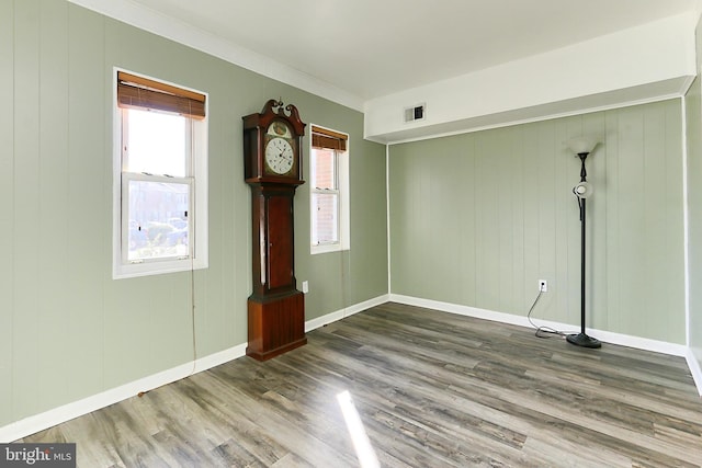 spare room featuring visible vents, crown molding, baseboards, and wood finished floors