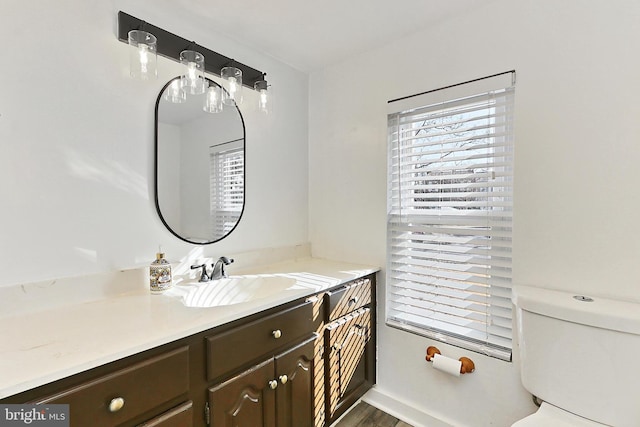 bathroom featuring vanity, toilet, and a healthy amount of sunlight