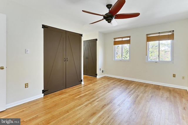 unfurnished bedroom with light wood-style flooring, a ceiling fan, and baseboards