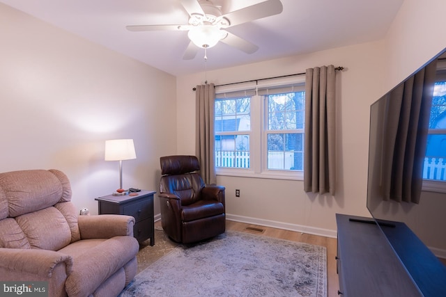 sitting room featuring light wood finished floors, baseboards, visible vents, and a ceiling fan