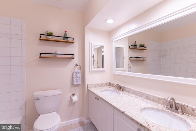 full bath with toilet, double vanity, baseboards, and a sink