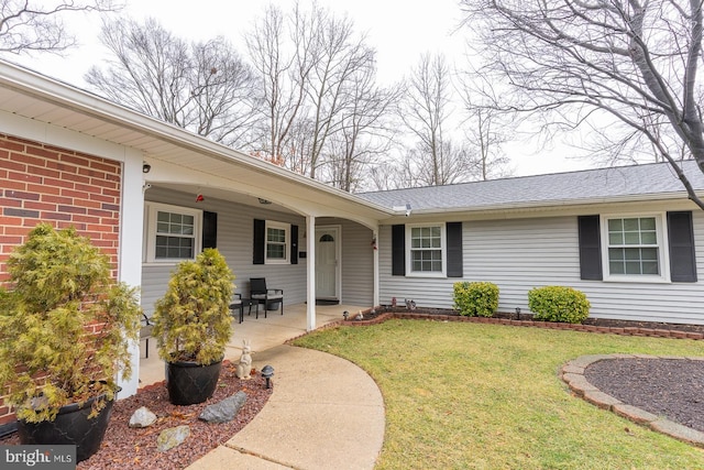 view of front of property with a patio area, brick siding, and a front yard