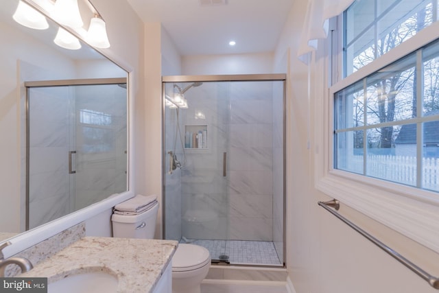 bathroom with a stall shower, vanity, and toilet