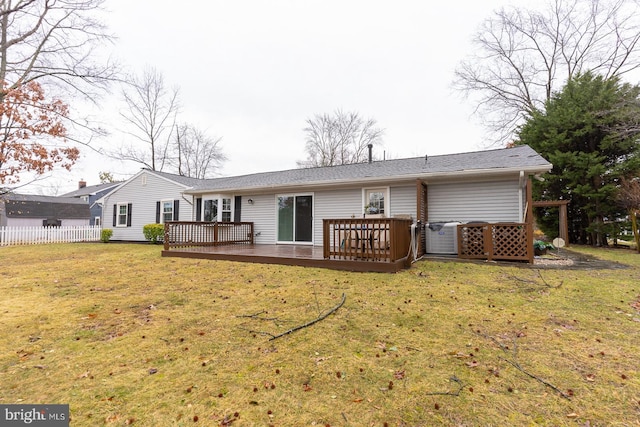 rear view of house featuring fence, a lawn, and a wooden deck