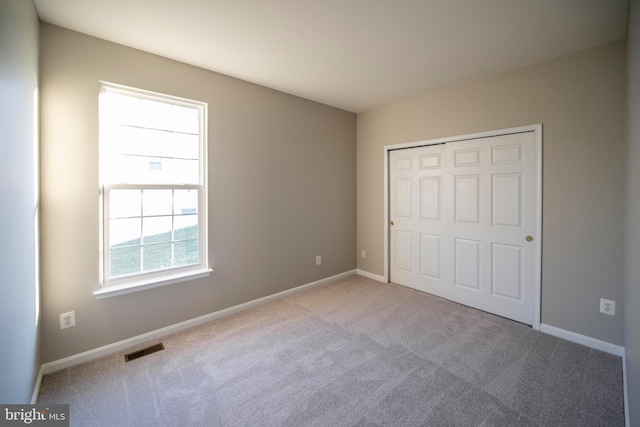 unfurnished bedroom featuring carpet, a closet, visible vents, and baseboards