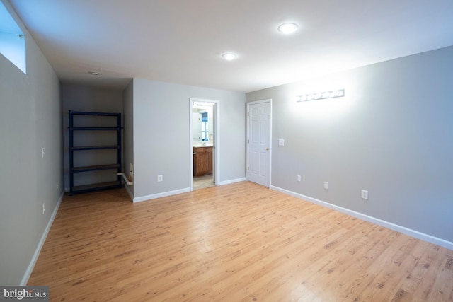 unfurnished bedroom featuring light wood-type flooring, ensuite bath, and baseboards