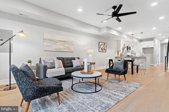 living room featuring baseboards, visible vents, a ceiling fan, light wood-type flooring, and recessed lighting