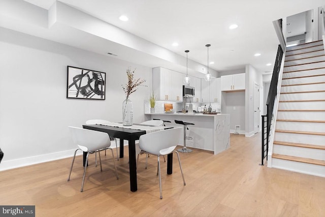 dining area with light wood finished floors, recessed lighting, visible vents, baseboards, and stairs