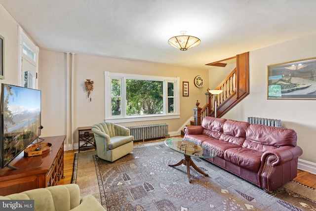 living room with radiator, stairs, baseboards, and wood finished floors