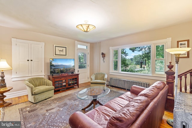 living room featuring stairs, radiator, baseboards, and wood finished floors