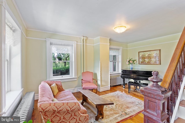 living area with stairs, light wood finished floors, radiator heating unit, and baseboards