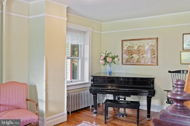 sitting room featuring radiator, baseboards, ornamental molding, and wood finished floors