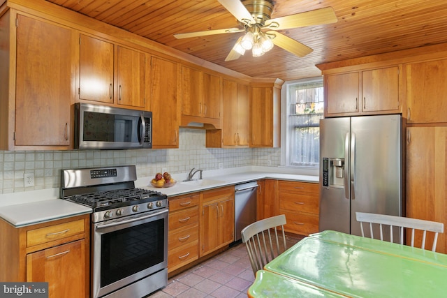 kitchen with a sink, backsplash, stainless steel appliances, and light countertops