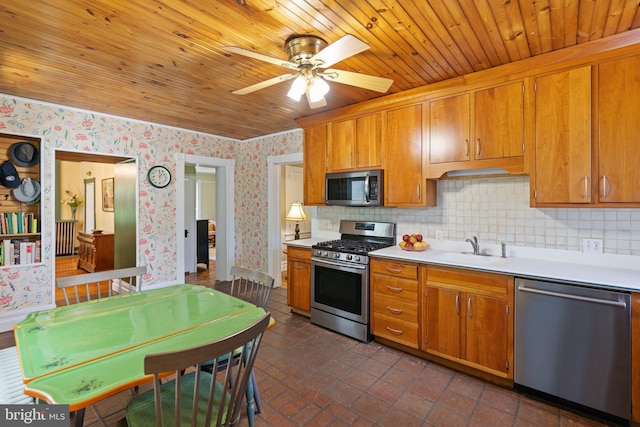 kitchen with wallpapered walls, brown cabinetry, stainless steel appliances, light countertops, and a sink