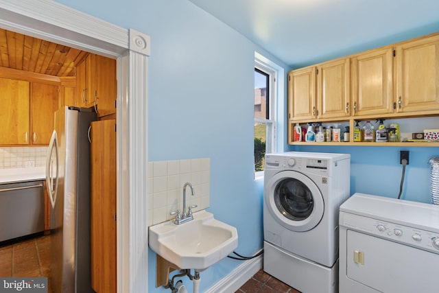 laundry area featuring cabinet space, dark tile patterned flooring, a sink, and washing machine and clothes dryer