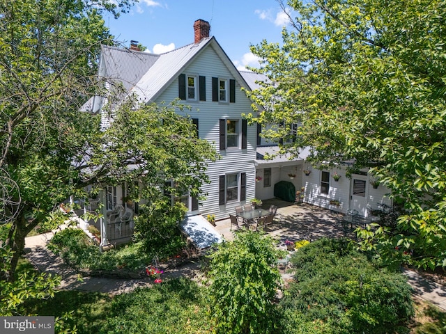 view of front of property with metal roof, a chimney, and a patio area