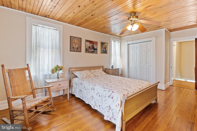 bedroom featuring light wood-style flooring, multiple windows, ornamental molding, and a closet