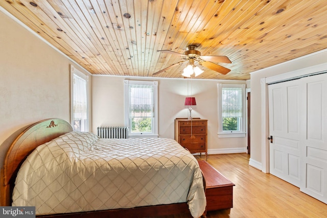 bedroom featuring wood ceiling, multiple windows, light wood-style flooring, and radiator heating unit