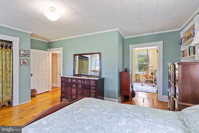 bedroom featuring light wood finished floors, baseboards, and ornamental molding