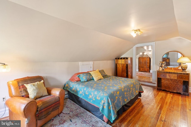 bedroom with lofted ceiling and wood finished floors