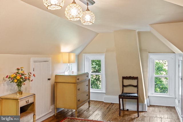 living area with vaulted ceiling, baseboards, and wood finished floors