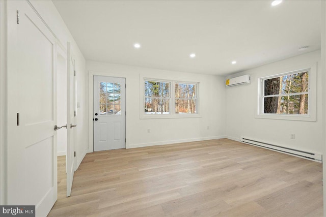 interior space with recessed lighting, light wood-style flooring, a baseboard heating unit, a wall mounted air conditioner, and baseboards