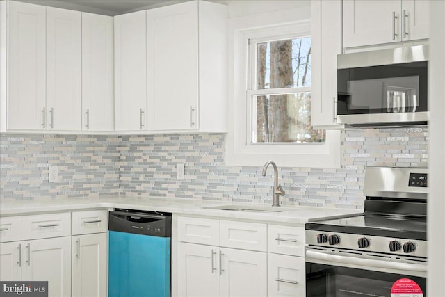 kitchen with decorative backsplash, appliances with stainless steel finishes, light countertops, white cabinetry, and a sink