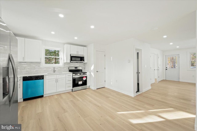 kitchen featuring tasteful backsplash, light countertops, appliances with stainless steel finishes, white cabinets, and a sink