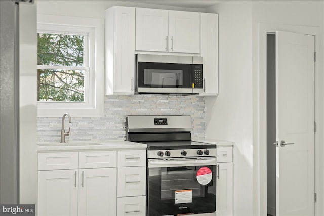 kitchen featuring stainless steel appliances, white cabinets, light countertops, and a sink