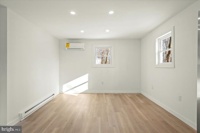 interior space featuring a baseboard heating unit, an AC wall unit, a healthy amount of sunlight, and light wood-style floors