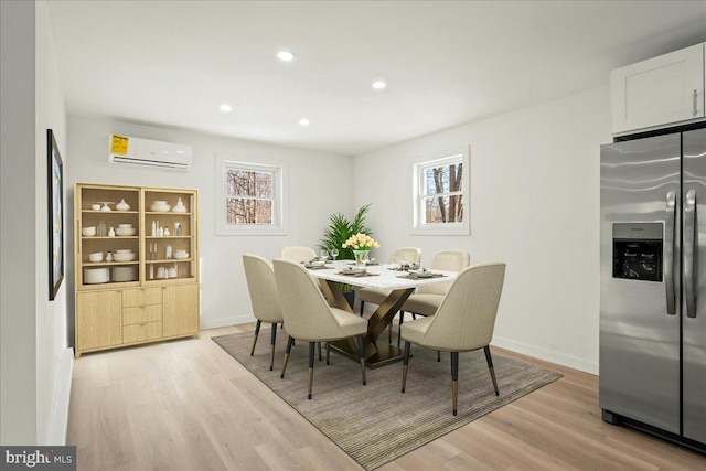 dining space with a wall unit AC, light wood-style flooring, and baseboards