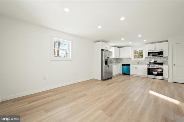 kitchen with light countertops, light wood-style flooring, decorative backsplash, appliances with stainless steel finishes, and white cabinets