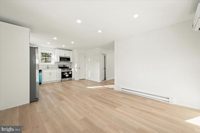 unfurnished living room featuring a baseboard heating unit, recessed lighting, baseboards, and light wood finished floors