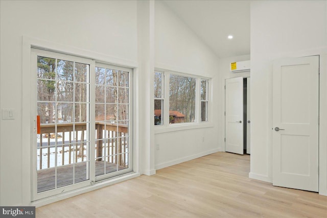 interior space featuring light wood-style floors, baseboards, an AC wall unit, and recessed lighting