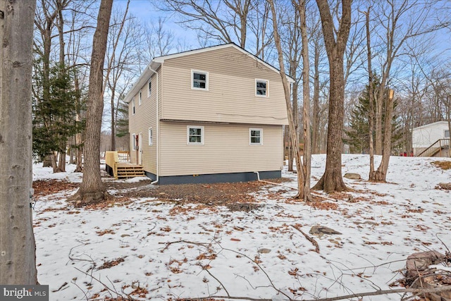 snow covered rear of property featuring a deck